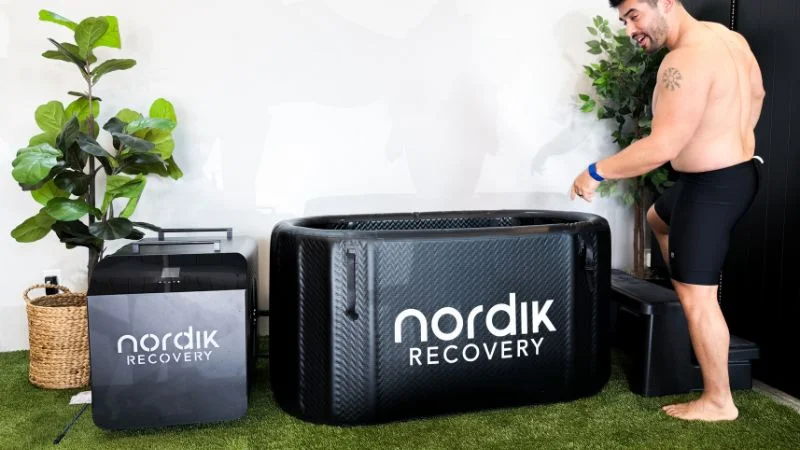 A man stepping into the Nordik Recovery cold plunge tub