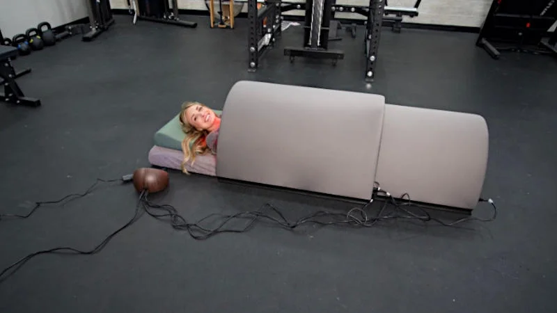 A person smiling at the camera while in a Sunlighten Solo Sauna
