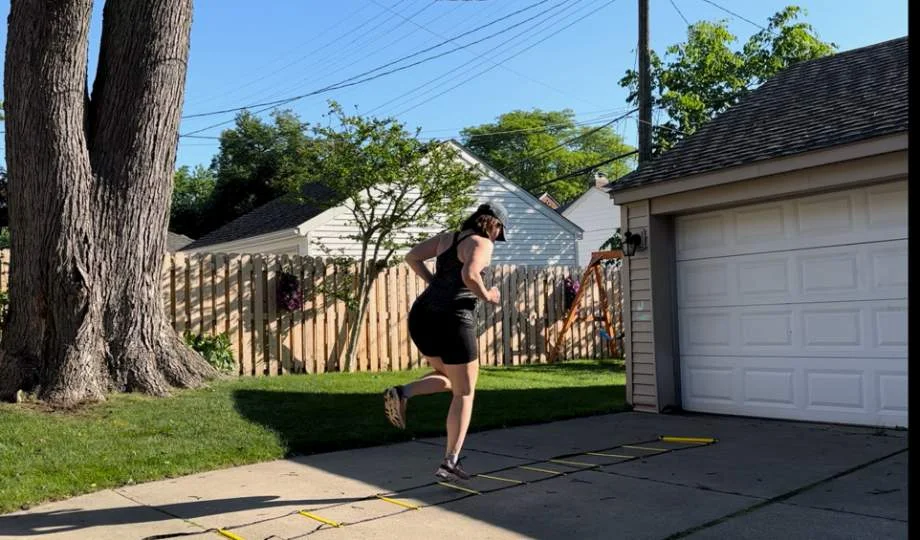 A woman appears to be playing hopscotch with the Juvale Agility Ladder.