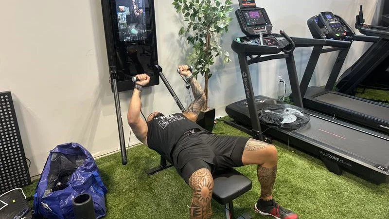 A person bench pressing with the Tonal 2 Smart Home Gym.
