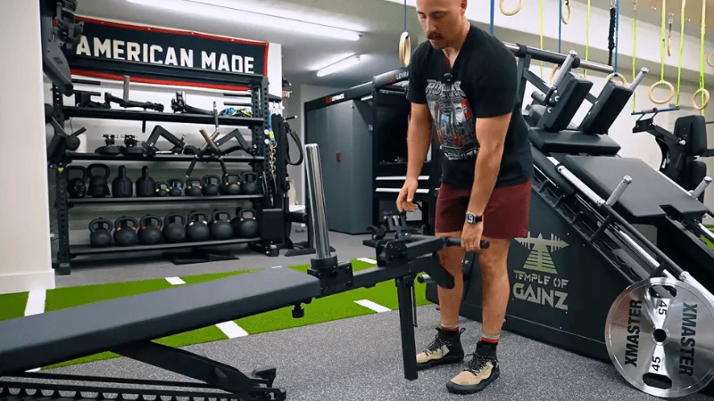Our tester looking at and testing one of the many accessories available for the Tib Bar Guy Apex Adjustable Bench