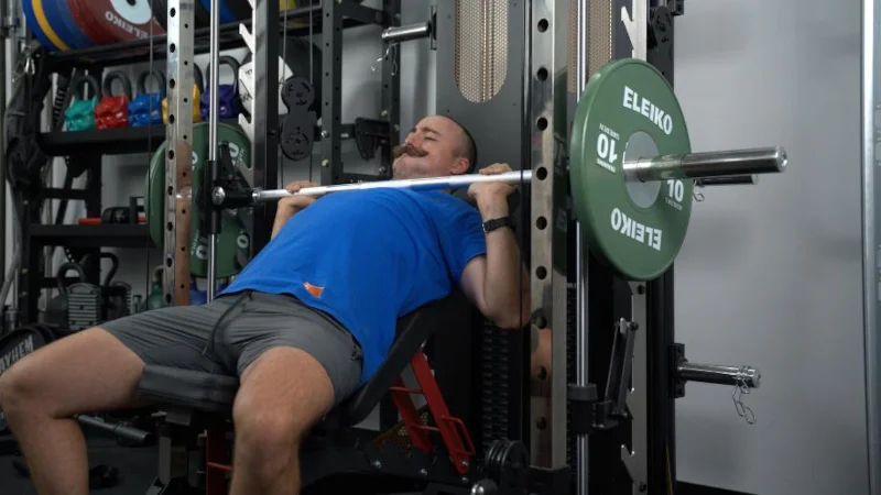Coop does a barbell bench press on a smith machine