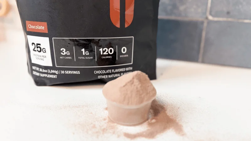 ggr-nobull-grass-fed-whey-protein-isolate-full-scoop-next-to-bag A scoop of NOBULL Grass-Fed Whey Protein Isolate sitting in front of an open container