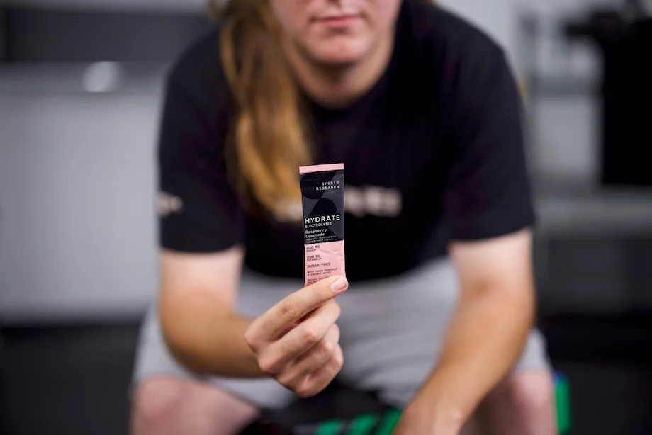 An image of a person holding a packet of Sports Research Hydrate electrolytes