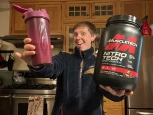 muscletech nitro tech woman holding canister and sahker