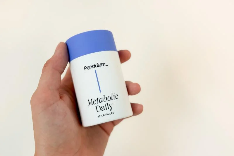 A product tester holding a container of Pendulum Metabolic Daily