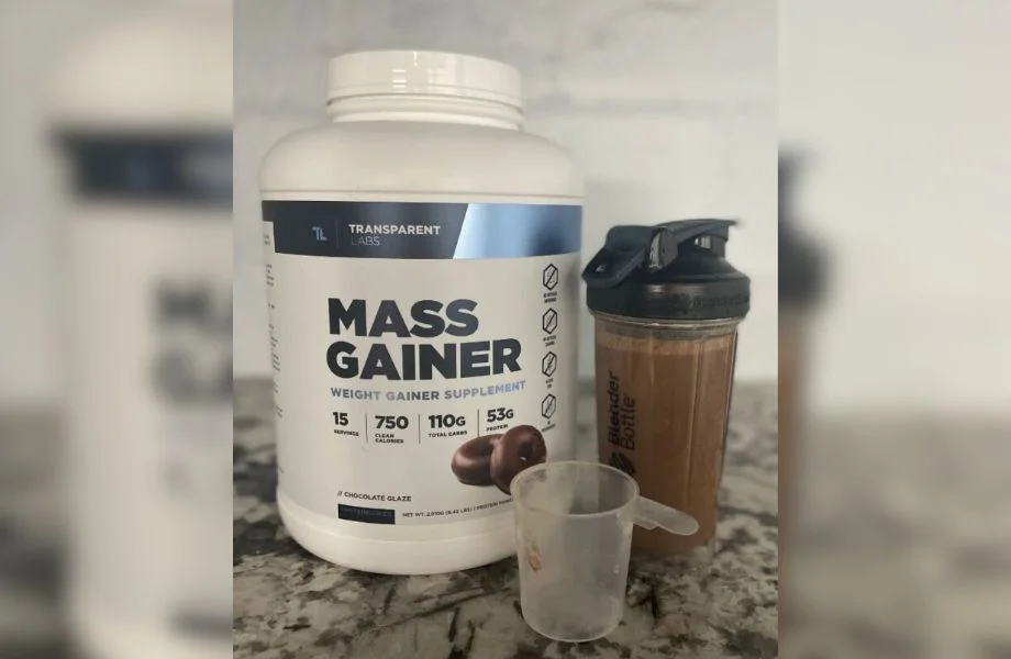 A container of Transparent Labs Mass Gainer set on a counter with a mixed shaker bottle