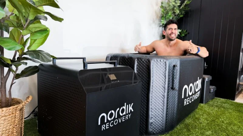 A man giving a thumbs up while sitting in the Nordik Recovery cold plunge