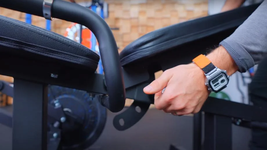 A close look as Coop adjusts the back pad for a RitFit PLC01 Leg Extension Curl Machine