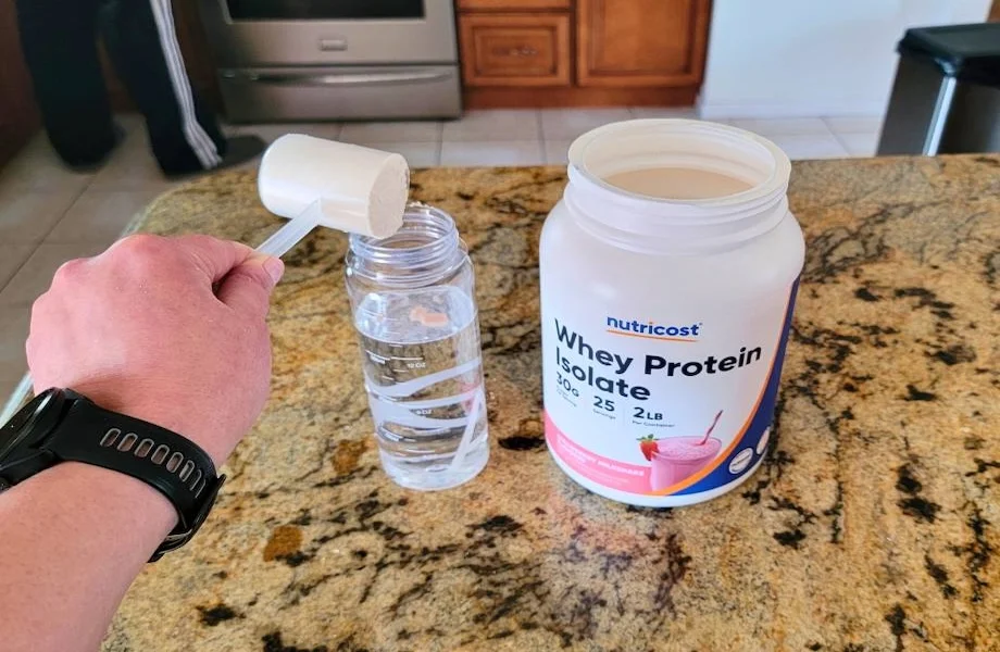 Our tester adding a scoop of Nutricost Whey Protein Isolate protein powder to their shaker bottle