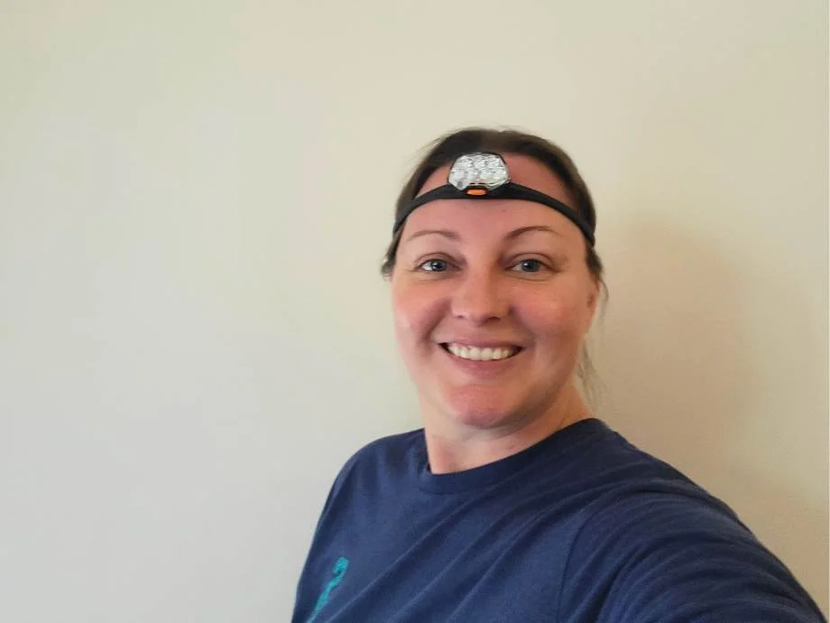 A smiling woman wears a PETZL Iko Core Headlamp