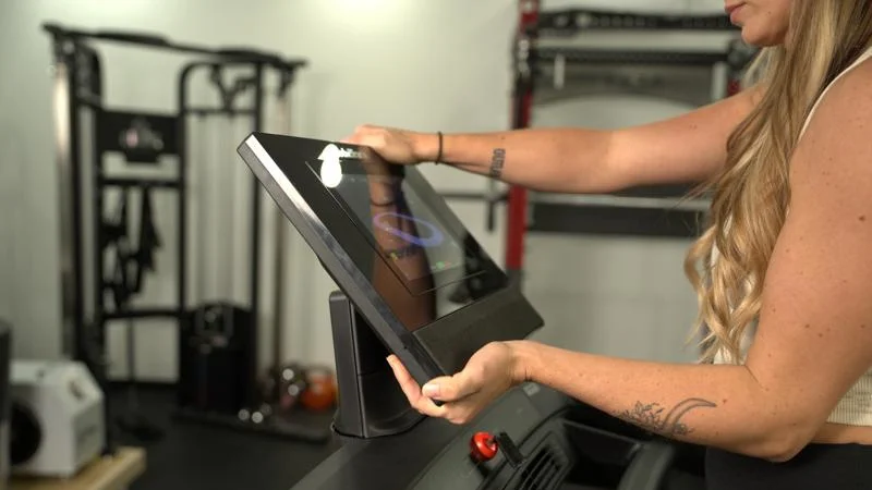 Side view as two hands reach out and tilt the screen on a NordicTrack Commercial 1250 treadmill