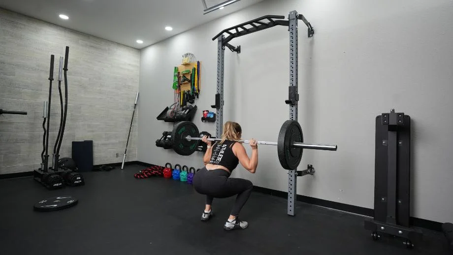 A woman performs back squats while using the PRx Profile Folding Squat Rack