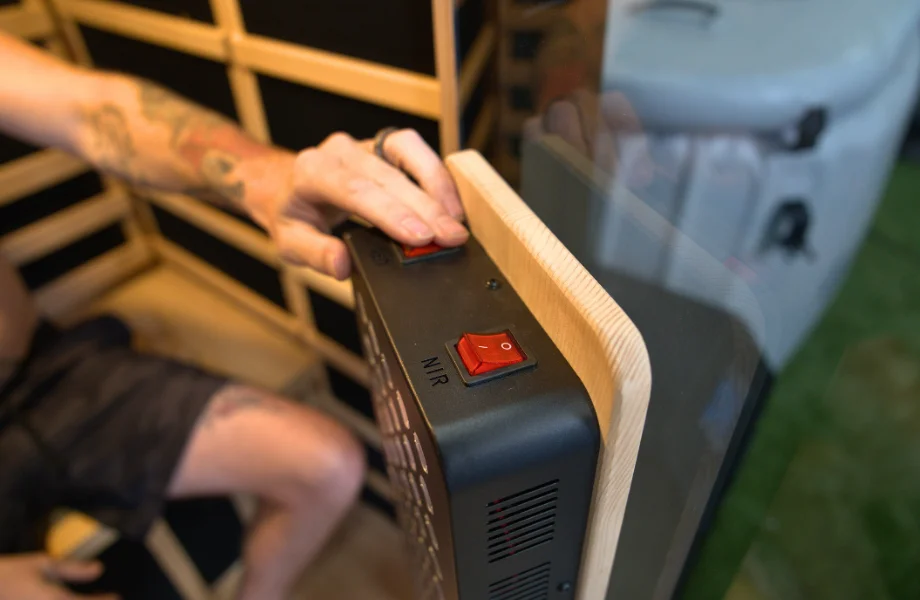 Our tester toggling on the red light therapy panel featured on the SaunaBox Solara infrared sauna