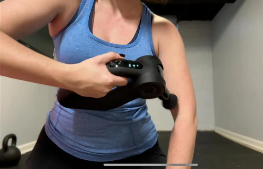 A woman using the Bob and Brad D6 Pro Massage Gun on her biceps