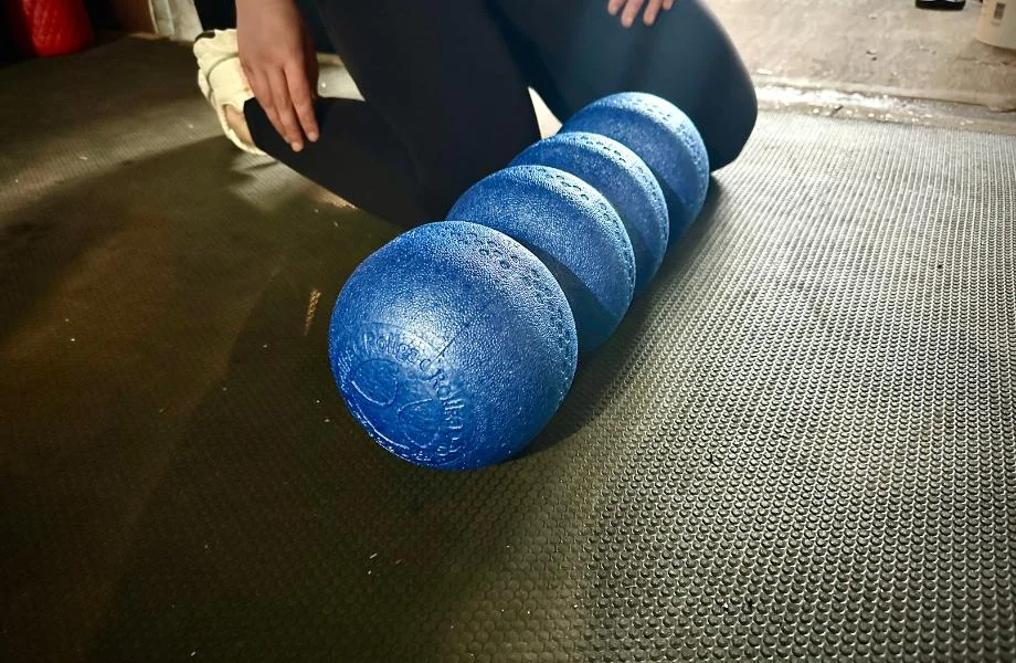 A person kneels by a Rollga Medium Density Foam Roller during a recovery session