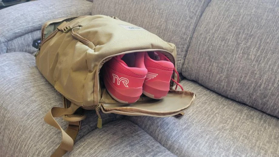 Shoes are shown hanging out of a  KNKG CORE Gym Backpack