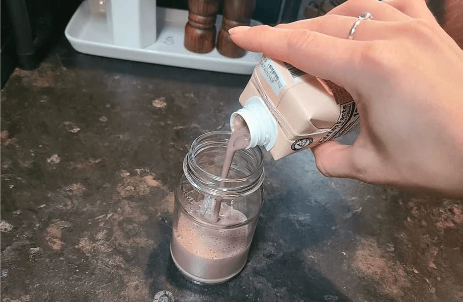 Our tester pouring their Evolve Plant-Based Protein Shake into a mason jar for consumption