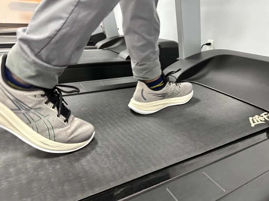 A close look at someone walking with Asics GEL-Cumulus 26 recovery sneakers.