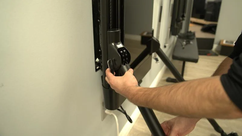 A person adjusts the lifting arm on a Tonal 2 Smart Home Gym.