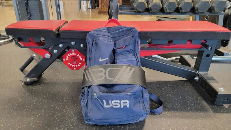 A gym bag leans against a weight bench.