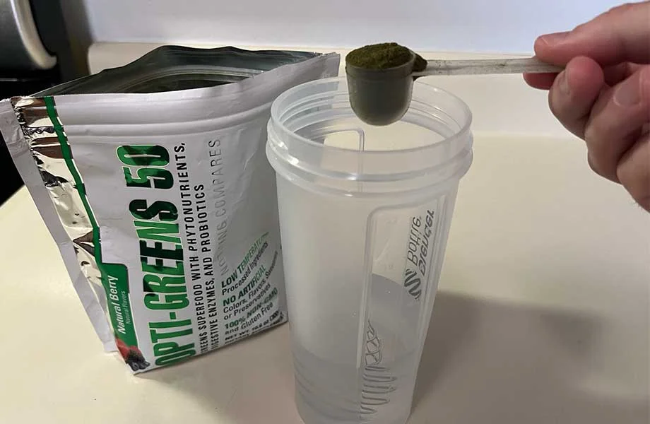 Man holding a scoop of Opti Greens 50