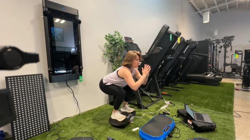Our tester doing squats on a Merach CV30 Vibration Plate.