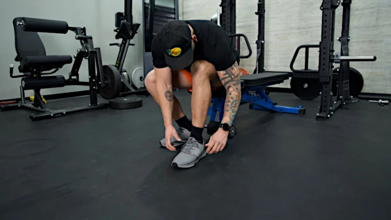 A man leans down to tie a pair of Kuru Atom shoes.
