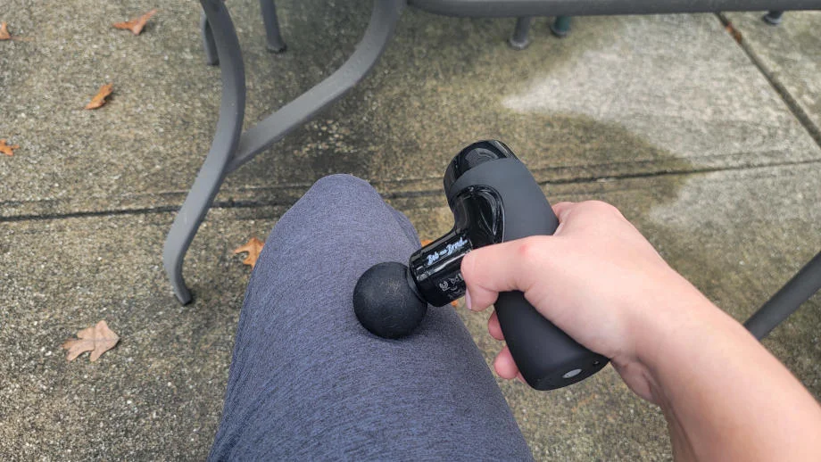 A person uses the Bob & Brad M7 Plus mini massage gun on their quads.